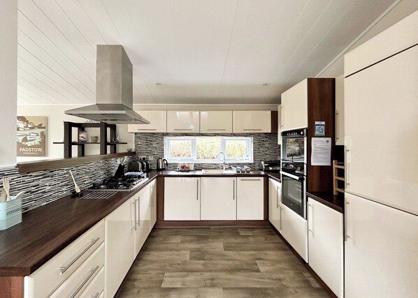 Cozinha moderna com ilha central, eletrodomésticos de aço inoxidável e janela que proporciona luz natural.