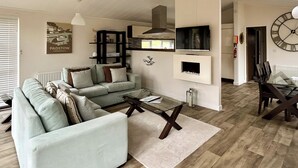 A living room with a sofa, coffee table, and a fireplace. - Country Lodge Four Platinum (Tintagel)