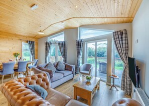 A spacious living room with a wooden ceiling, a sofa, a coffee table, and a television. - 3 bedroom accommodation in Ellesmere (Ellesmere)