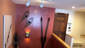 A hallway with a red wall, wooden door, and a staircase with a wooden handrail. - All the comforts of home. Amazing mountain views from both floors! (Durango)