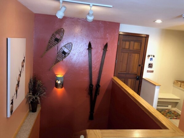 A hallway with a red wall, wooden door, and a staircase with a wooden handrail. - All the comforts of home. Amazing mountain views from both floors! (Durango)