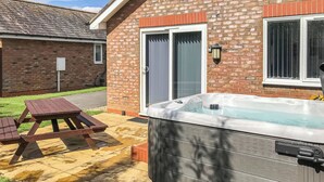 Een bakstenen huis met een hottub, een picknicktafel en een raam met zonwering.