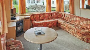 A cozy RV interior with a sectional sofa, a small table, and a TV. - 2 bedroom accommodation in Clarach Bay, Nr Aberystwyth (Clarach Bay, Nr Aberystwyth)