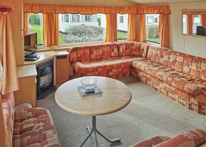 A cozy RV interior with a sectional sofa, a small table, and a TV.