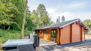 Une cabane en rondins dotée d’un bain à remous et d’un espace salon extérieur.