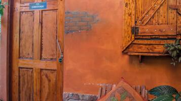A wooden door labeled "CORCOVADO," a bench with a quilt, and a potted plant.