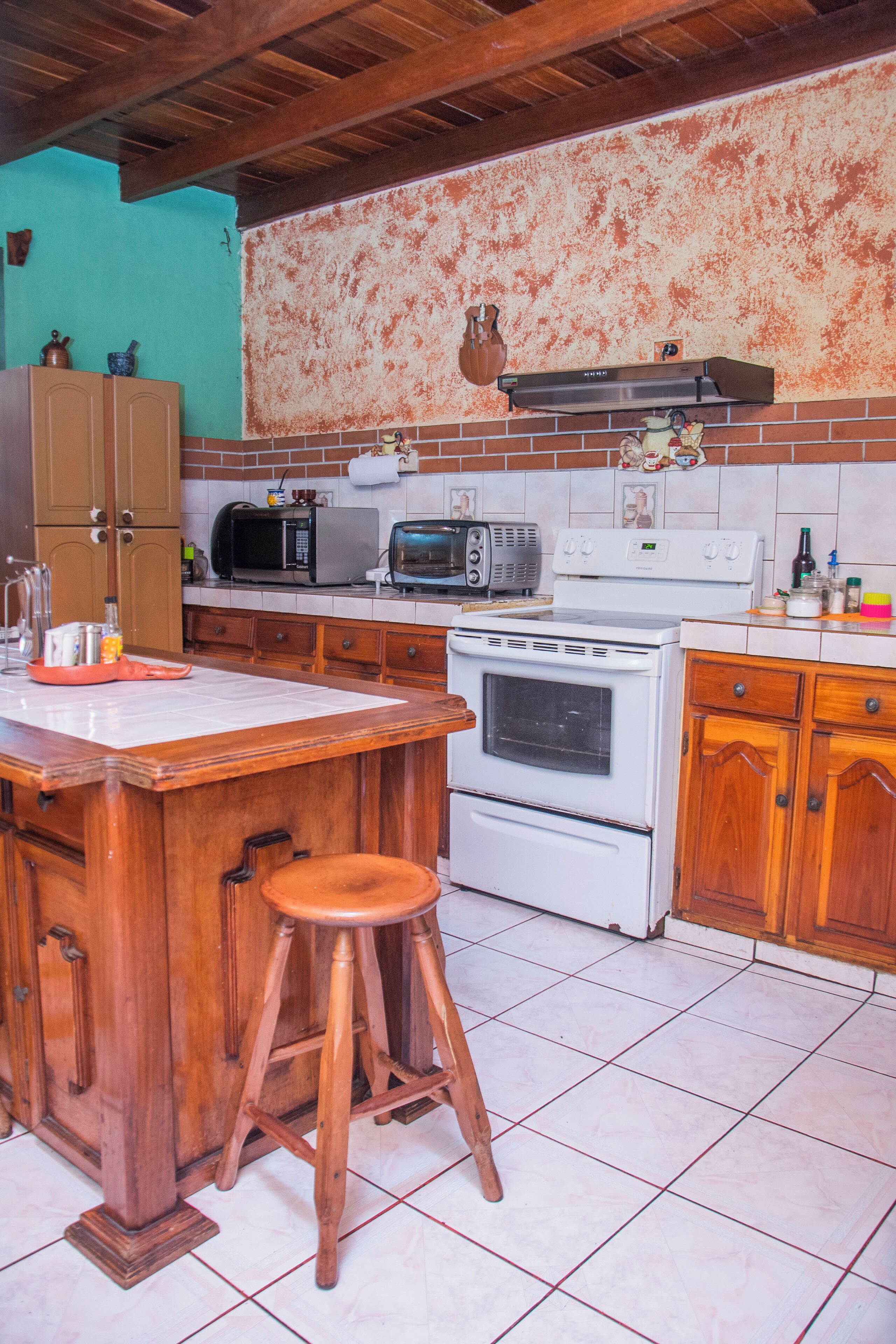A kitchen with wooden cabinets, a white stove, a microwave, and a tiled backsplash.