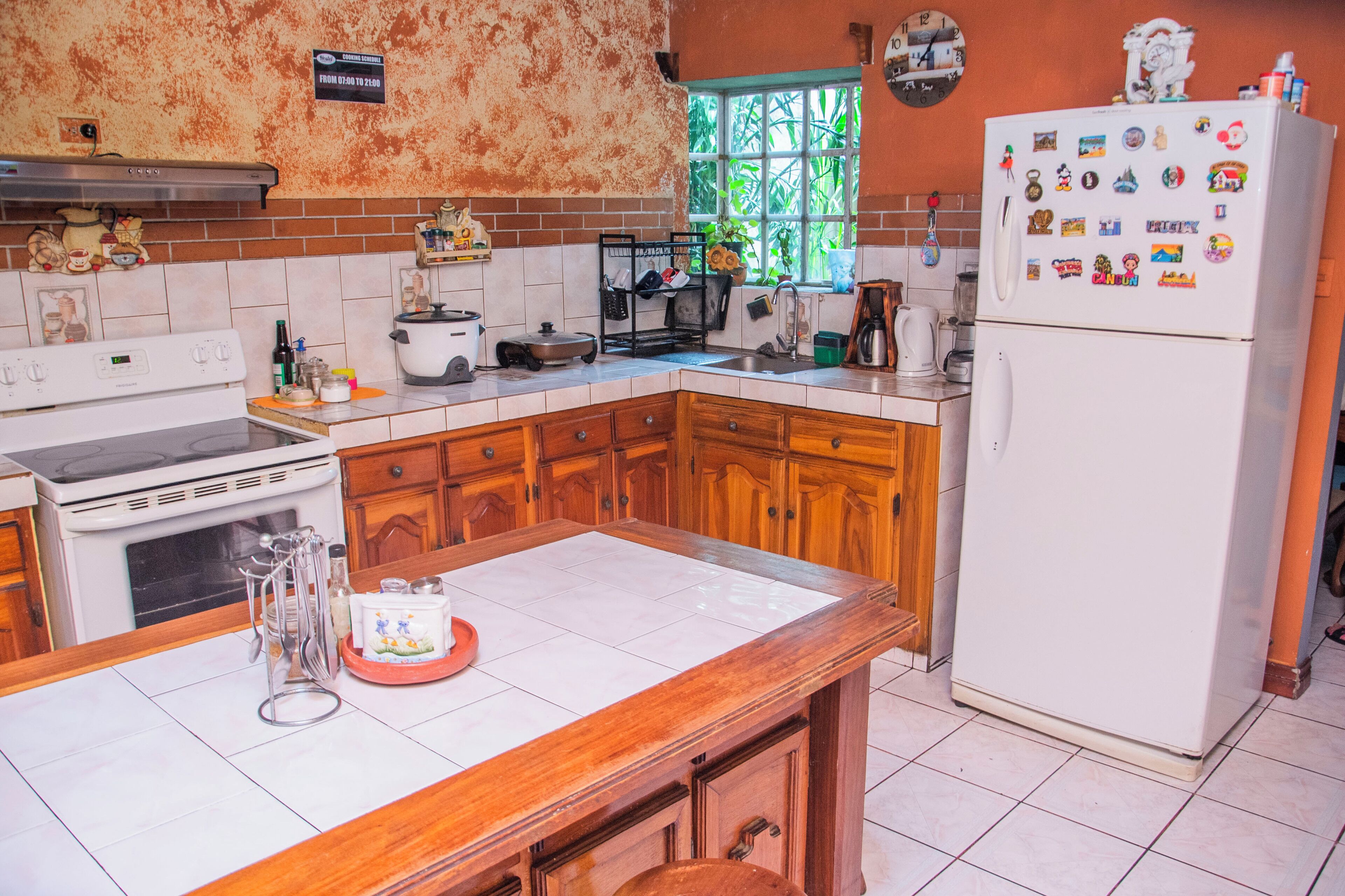 Una cocina con armarios de madera, una estufa blanca y un refrigerador con imanes.
