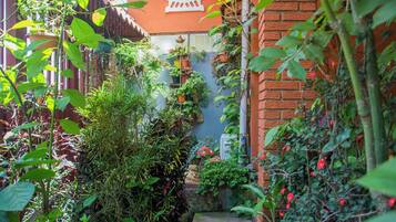 Un estrecho sendero de jardín que lleva a un edificio con un muro de ladrillo rojo y un banco blanco.