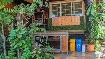 Un espace extérieur abrité, doté de poutres en bois, de plantes en pot et d’un sol carrelé.