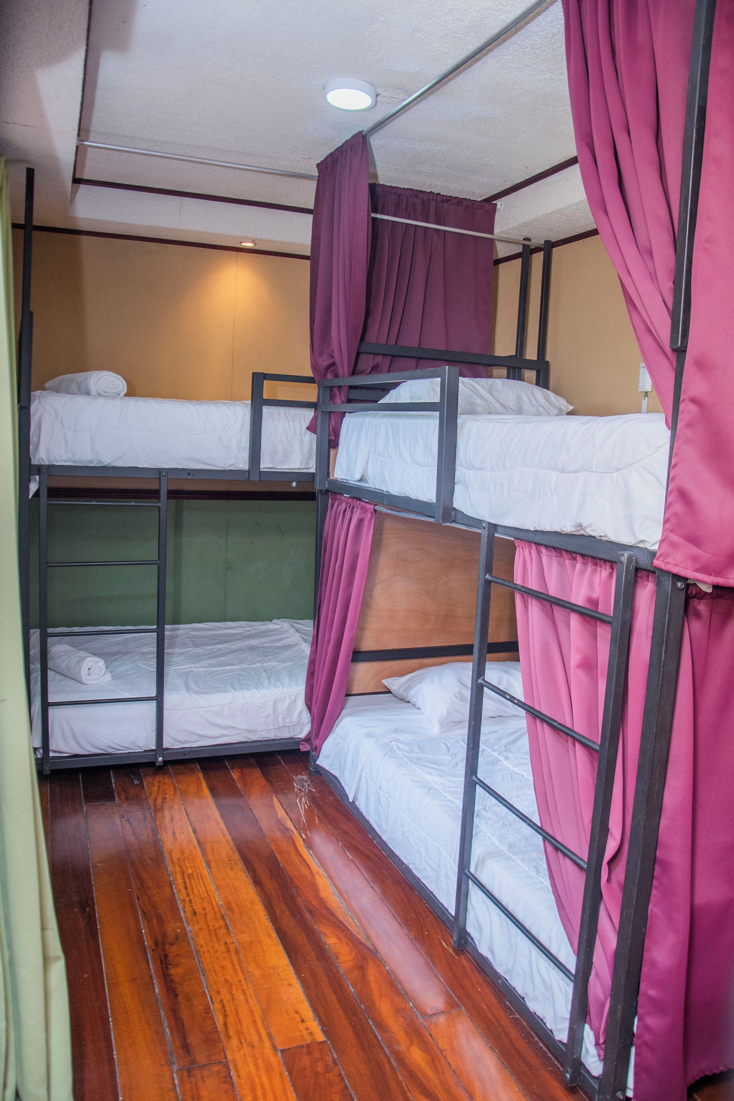 Dormitorio con literas, suelo de madera y cortinas.