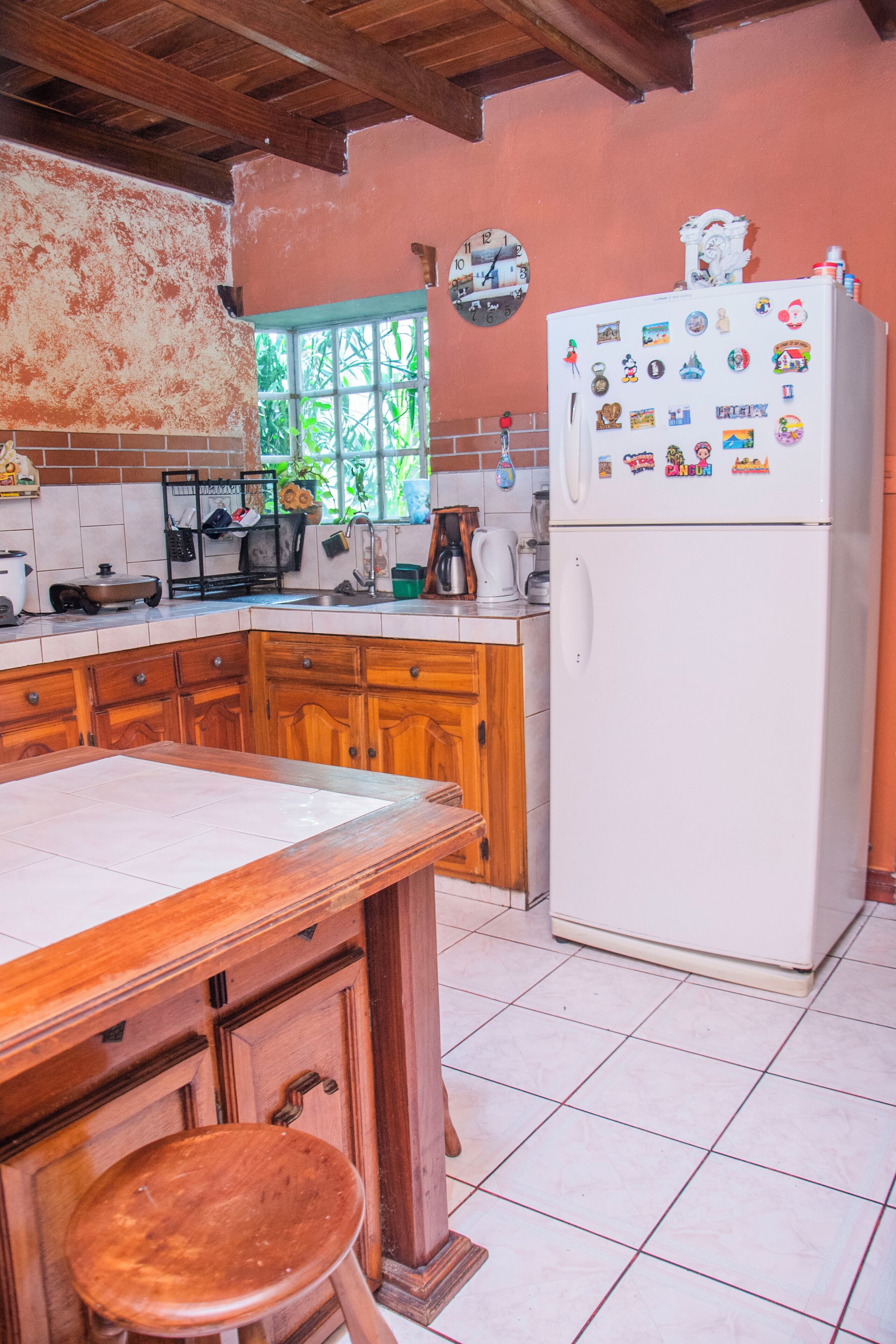 A kitchen with wooden cabinets, a white refrigerator, and a wooden table with a stool.