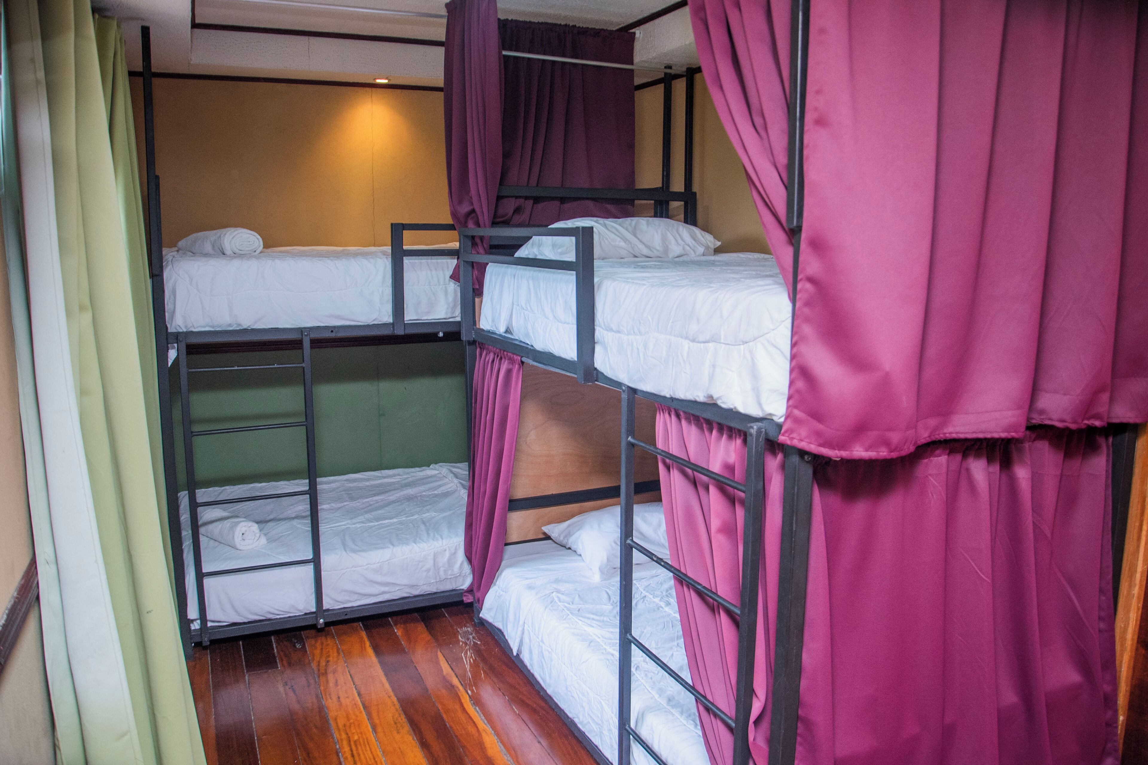 Dormitorio con literas, suelo de madera y cortinas moradas.