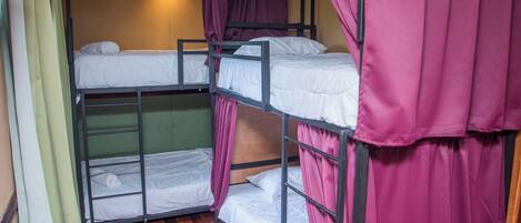 Dormitorio con literas, suelo de madera y cortinas moradas.