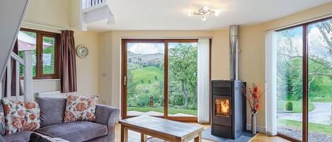 A living room with a sofa, a table, a fireplace, and a view of the outdoors.