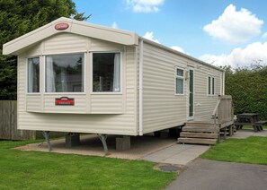 A caravan with a 'Carnaby Ashdale' sign, a front door, and a small porch area. - 2 bedroom accommodation in Cowden, Nr Hornsea (Cowden, Nr Hornsea)