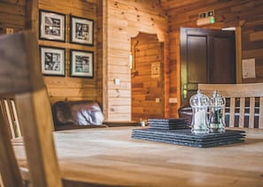 A wooden interior with framed pictures on the wall, a table with salt and pepper shakers, and a leather chair.