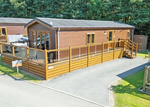 A wooden cabin with a balcony, a car parked in front, and a 'For Sale' sign. - Outstanding holiday home offering spacious and comfortable open plan living. (Old Langho, Ribble Valley)