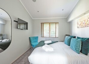 A hotel room with a large bed, a sitting area with a chair, a window with blinds, a mirror, and a radiator. - Outstanding holiday home offering spacious and comfortable open plan living. (Old Langho, Ribble Valley)