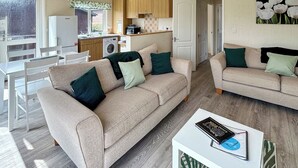 A cozy living room with two sofas, a dining table, and a kitchen area with wooden cabinets.