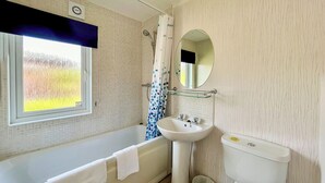 A bathroom with a bathtub, a sink, a toilet, and a window with a view of greenery.