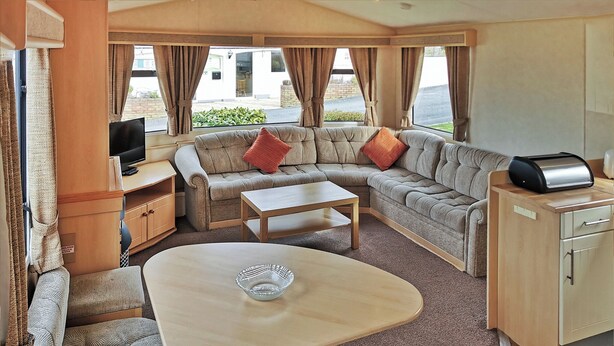 A cozy RV interior with a sofa, a coffee table, a TV, and a kitchenette. - 3 bedroom accommodation in Clarach Bay, Nr Aberystwyth (Clarach Bay, Nr Aberystwyth)