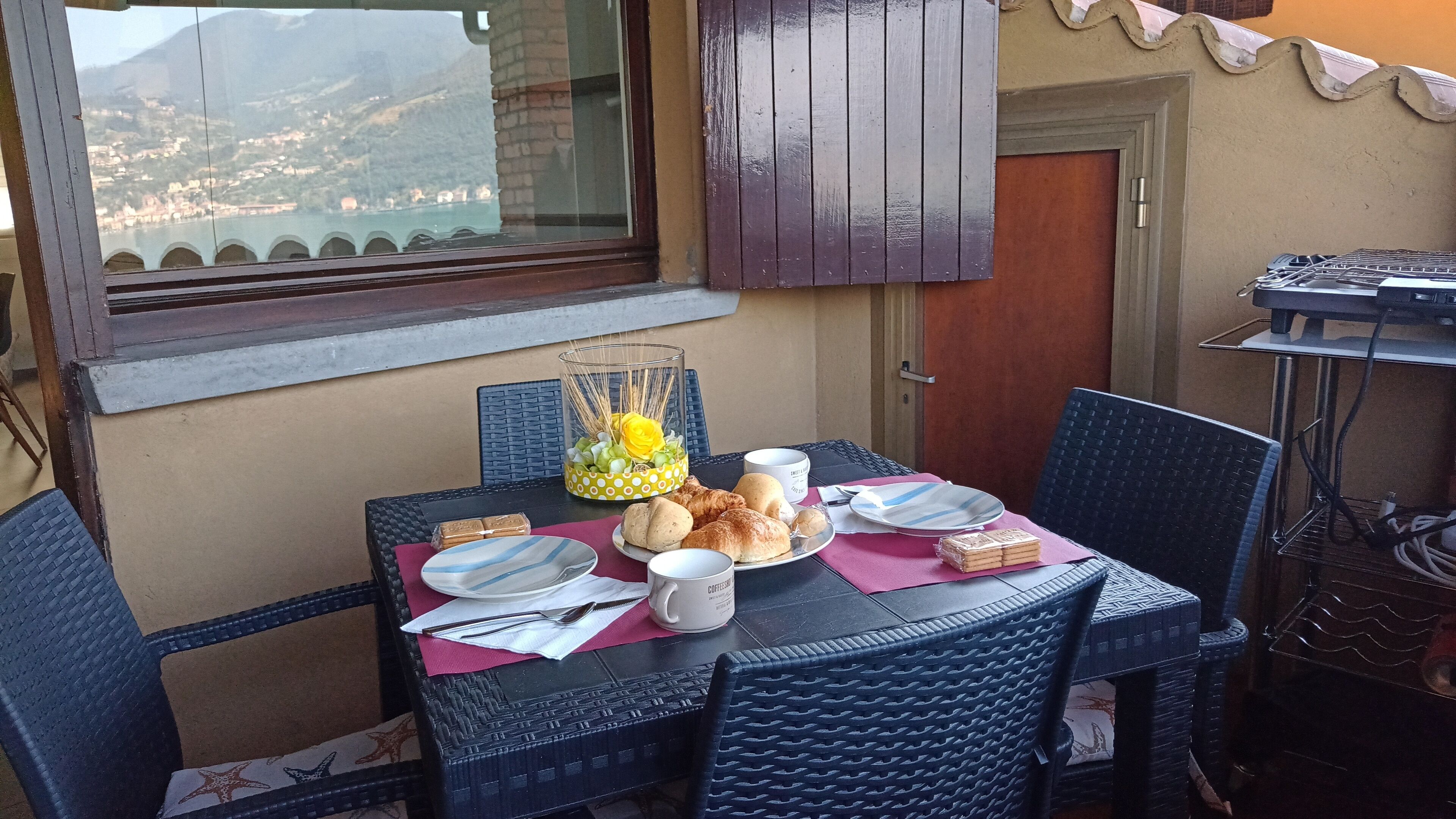 A dining table with chairs, plates, cups, and food items.