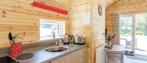 L’intérieur d’un chalet en bois comprend une cuisine, un coin repas et une fenêtre offrant une vue agréable.
