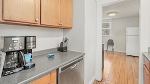 A kitchen with wooden cabinets, a coffee maker, a dishwasher, and a refrigerator.