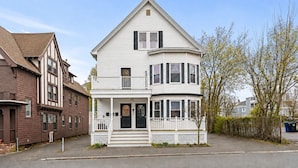 A two-story house with a front porch, a balcony, and a chimney.