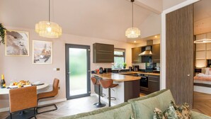 Eine moderne Küche mit Essbereich, Barhocker und einem grünen Sofa.