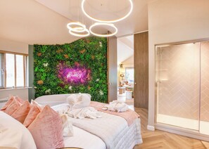 A modern bedroom with a bed, a green wall with a neon sign, a glass wardrobe, and a circular light fixture. - 1 bedroom accommodation in South Duffield, Nr York (South Duffield, Nr York)