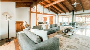 Un salon spacieux avec un haut plafond, une cheminée et de grandes fenêtres.