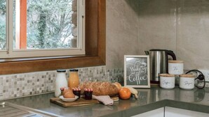 Une cuisine avec une fenêtre, une machine à café et des bocaux étiquetés « Thé », « Café » et « Sucre ».