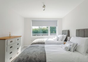 A bedroom with a bed, bedside tables, a dresser, and a window with a view of greenery. - 1 bedroom accommodation in South Molton, nr Barnstaple (South Molton, nr Barnstaple)