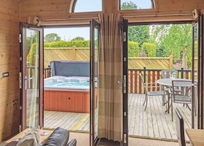 A hot tub on a wooden deck with a glass door leading to a patio area. - 2 bedroom accommodation in Easingwold (Easingwold)