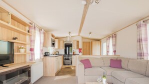 A compact living space with a kitchenette, a sofa, a television, and a dining table.