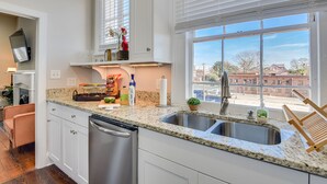 A modern kitchen with granite countertops, stainless steel appliances, and a large window offering a city view. - Stovall #3 Historic & walkable to downtown Augusta hotspots (Augusta)