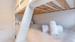 Ein Etagenbett mit weißer Bettwäsche und zwei gerollten Handtüchern.
