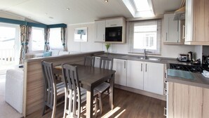 Una cocina moderna con comedor, armarios de madera, microondas y ventana.