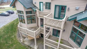 A multi-story building with a balcony on the ground floor, a garage with two cars, and a driveway. - EVL Chalet at Holiday Valley (Ellicottville)