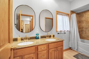 A bathroom with two sinks, wooden cabinets, and a shower area. - EVL Chalet at Holiday Valley (Ellicottville)