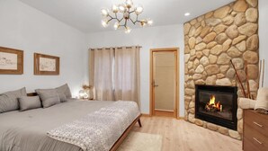 Un dormitorio con una cama grande, una chimenea de pared de piedra y un candelabro.