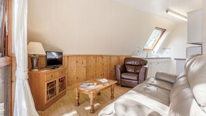 Ein gemütliches Wohnzimmer mit einer Couch, einem Fernseher, einem Holzschrank und einem Fenster mit Blick.