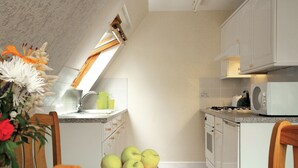 Eine Küche mit Esstisch, Stühlen, Obstschale, Spüle, Schränken und einer Mikrowelle.