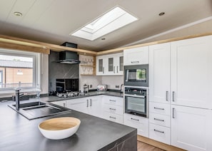 A modern kitchen with a large island, built-in appliances, and a skylight.
