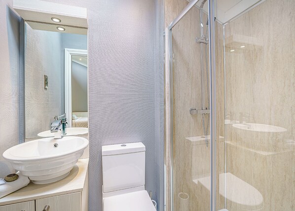 Une salle de bain moderne avec un grand miroir, un lavabo, des toilettes et une douche à parois de verre.