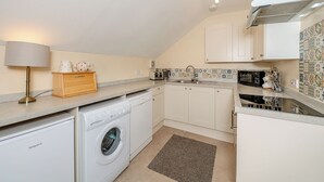 Een kleine keuken met een wasmachine, een koffiezetapparaat en een magnetron.
