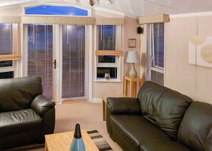 A living room with two leather sofas, a wooden coffee table, a lamp, and a window with blinds.