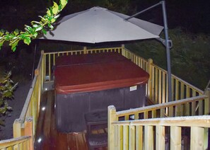A wooden deck with a hot tub and a large umbrella.